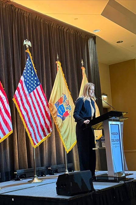 Person speaking at a podium with flags