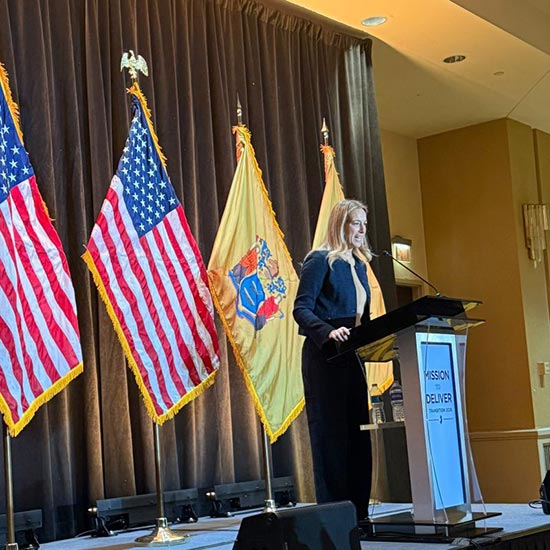 Laura giving speech in front of flags